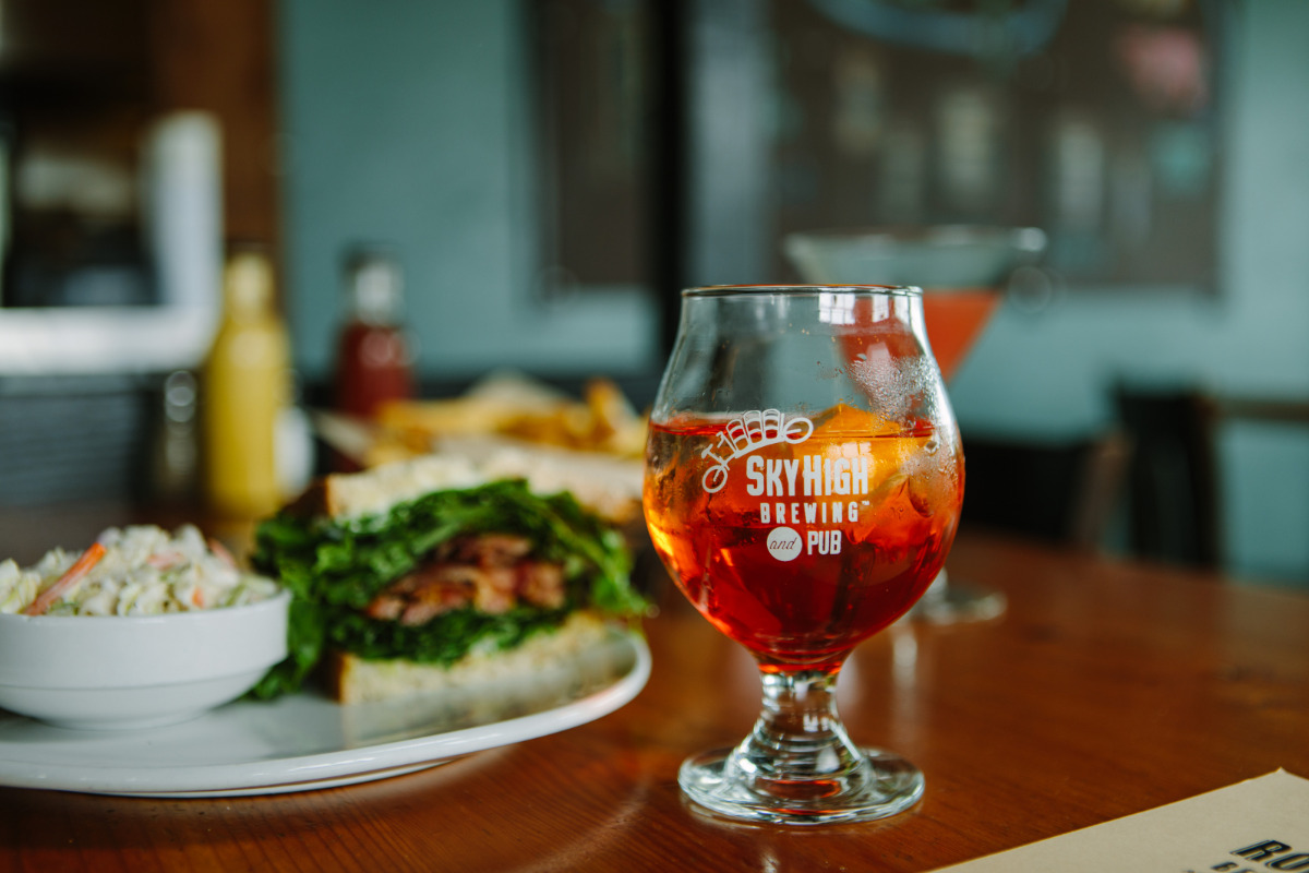 Sky High Brewing & Pub, Corvallis, Oregon - A Sky High logo glass of beer with a plate of food on a table inside Sky High Brewery