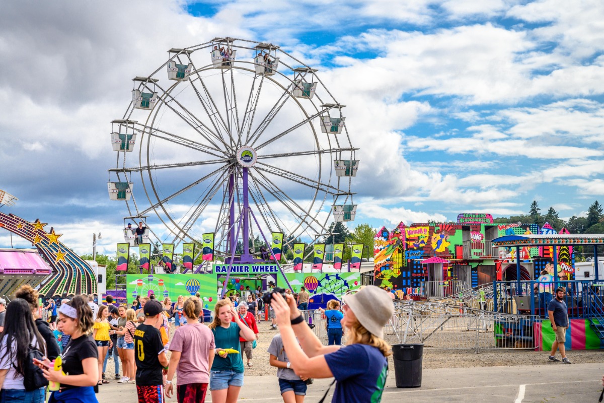 Benton County Fair, Corvallis, Oregon - Crowds in the foreground with the Ferris wheel and midway in the background - By Reed Lane Photography.