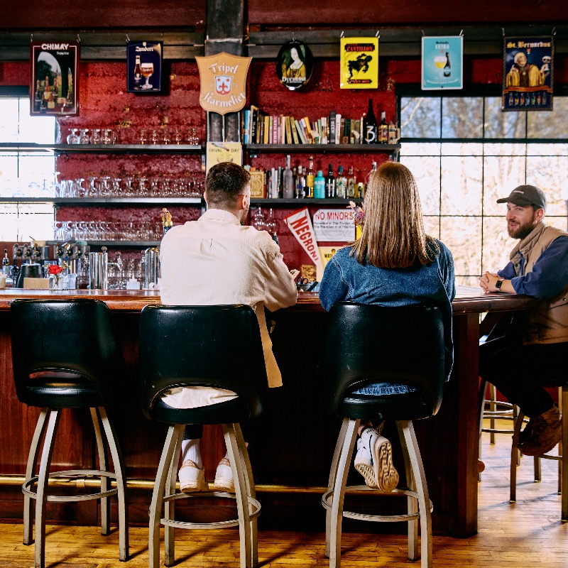 Three people enjoying drinks at the Biere Library's bar in Corvallis, Oregon.